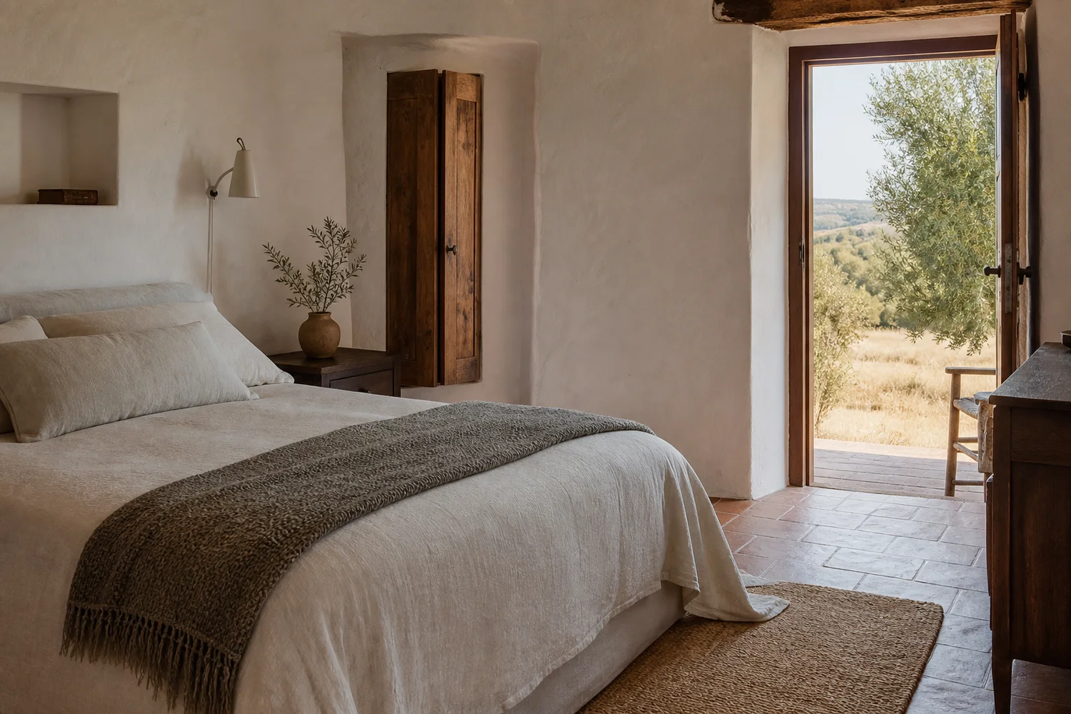 Suite rural com cama de linho e porta aberta para um olival